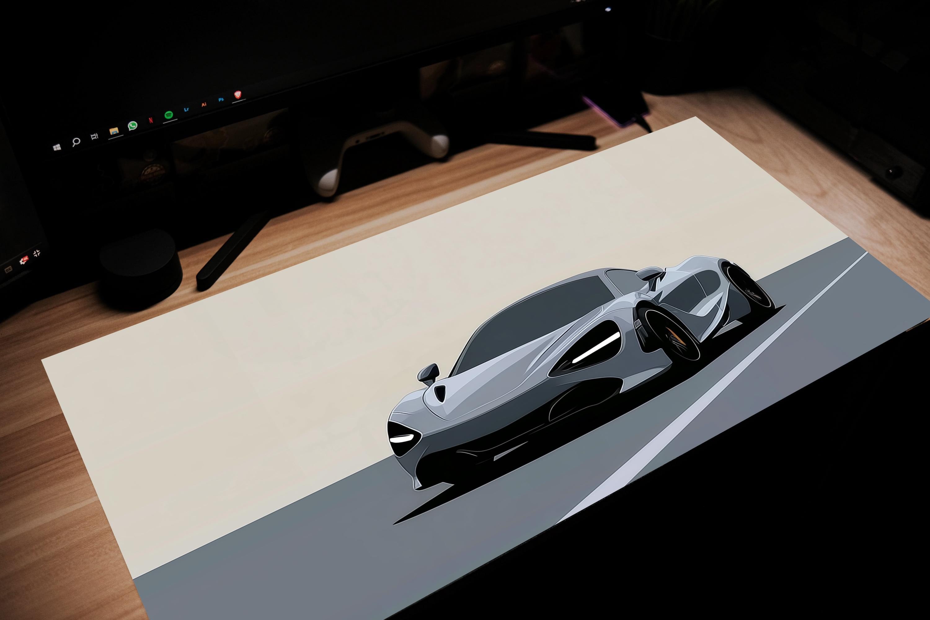 Modern sports car on a desk with a computer setup in the background